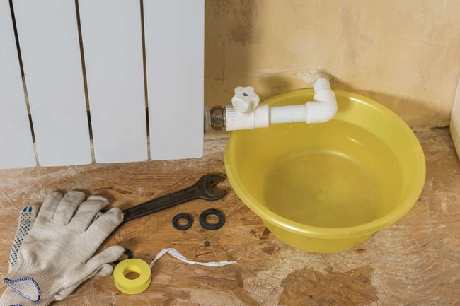 01 Guantes y herramientas de fontaneria durante la reparacion de una fuga en un radiador de calefaccion