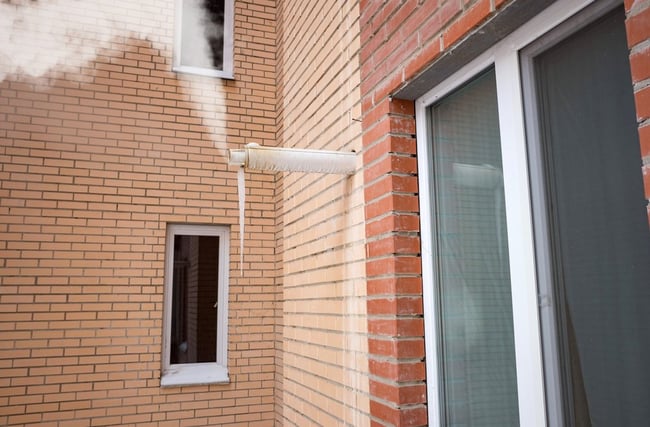 01 Humo blanco y agua saliendo de una chimenea horizontal en la pared de un edificio residencial