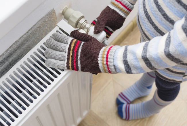 02 Persona con guantes tejidos y ropa de invierno manipulando el cabezal de un radiador de calefaccion