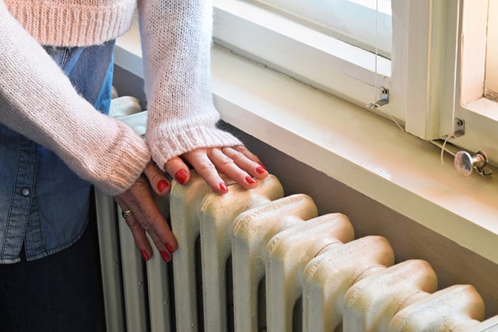 03 Mujer tocando el radiador de la calefaccion