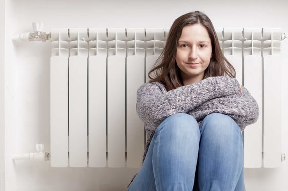 03 Una chica joven junto a un radiador de calefaccion que no esta calentando_Causas y soluciones para cuando la caldera Vaillant no calienta agua