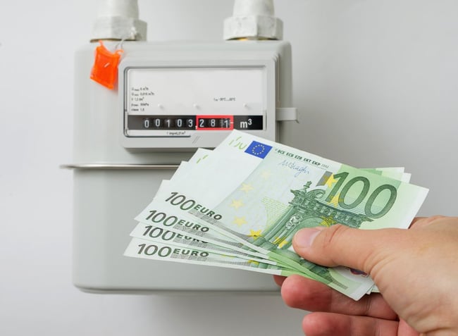03 Una mano sostiene 4 billetes de 100 euros junto a un gasometro como concepto del precio del gas