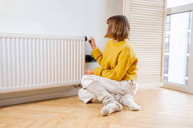 04 Una mujer manejando la temperatura de un radiador de calefaccion mediante una valvula termostatica