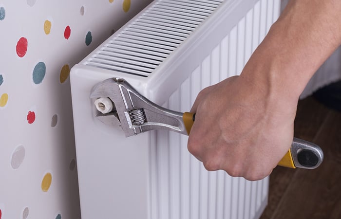 05 Un fontanero purgando un radiador de calefaccion con una llave de expansion