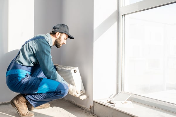 05 Un hombre emplazando un radiador de calefaccion en la pared junto a una ventana
