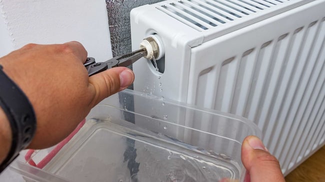 05 Un tecnico extrayendo agua de un radiador de calefaccion para bajar la presion de la caldera