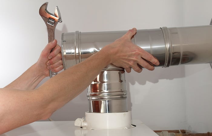 05 Una mano masculina instalando la salida de gases de una caldera de condensacion