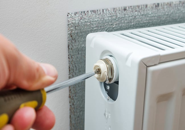 06 Un fontanero purgando un radiador de calefaccion usando un destornillador