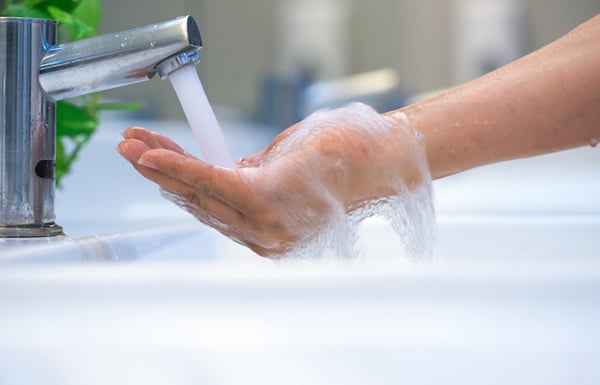 06 Una mano recibe agua caliente del grifo de un lavamanos