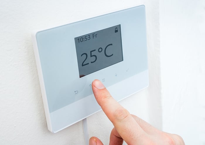 06. Una persona estableciendo en el termostato de calefacción la temperatura de 25 °C 