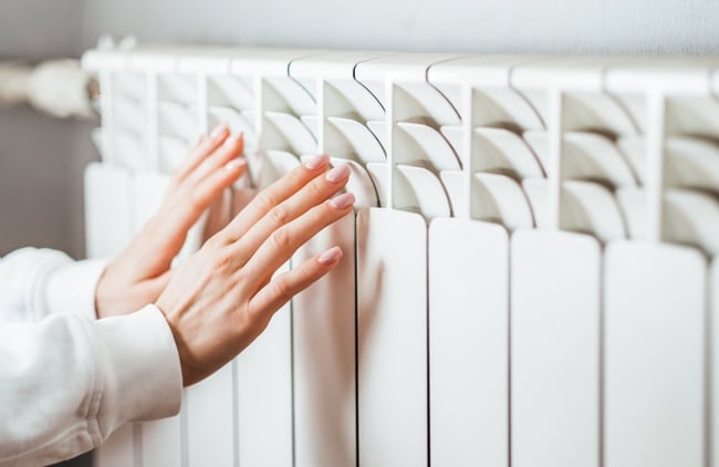 07 Unas manos femeninas comprobando la temperatura de un radiador de calefaccion