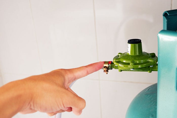 10 Una mano apuntando con el dedo hacia el regulador de una botella de gas