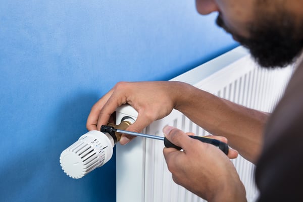 6 Close-up de un hombre usando un destornillador en una valvula termostatica de un radiador de calefaccion
